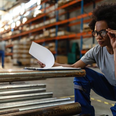 Black female warehouse worker examining check list before the distribution.